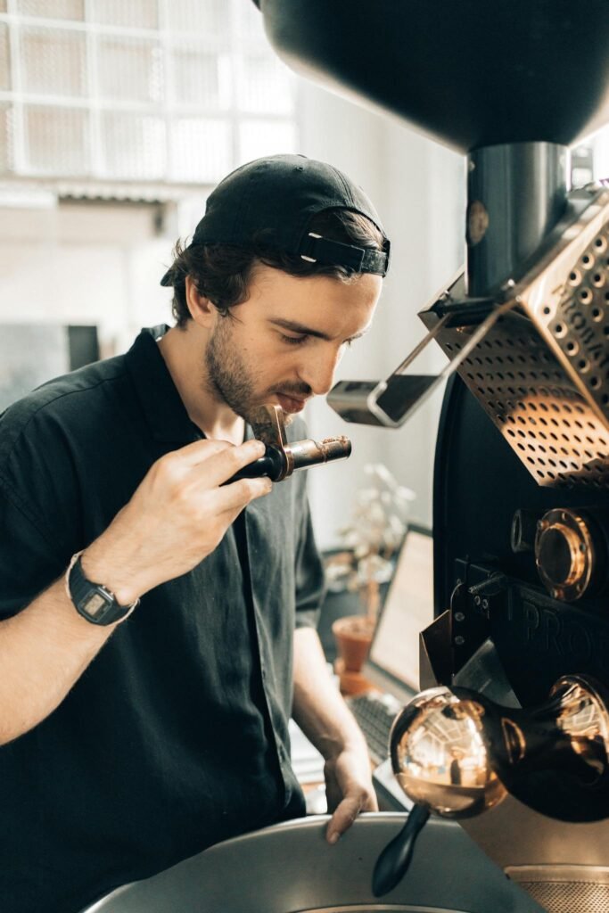 Barista deeply inhaling aroma of freshly roasted coffee beans in a modern cafe.