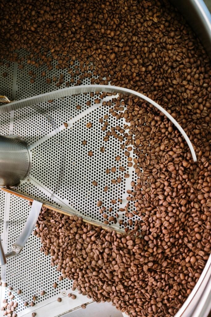 Coffee beans being roasted in an industrial steel roasting machine showing detailed processing.
